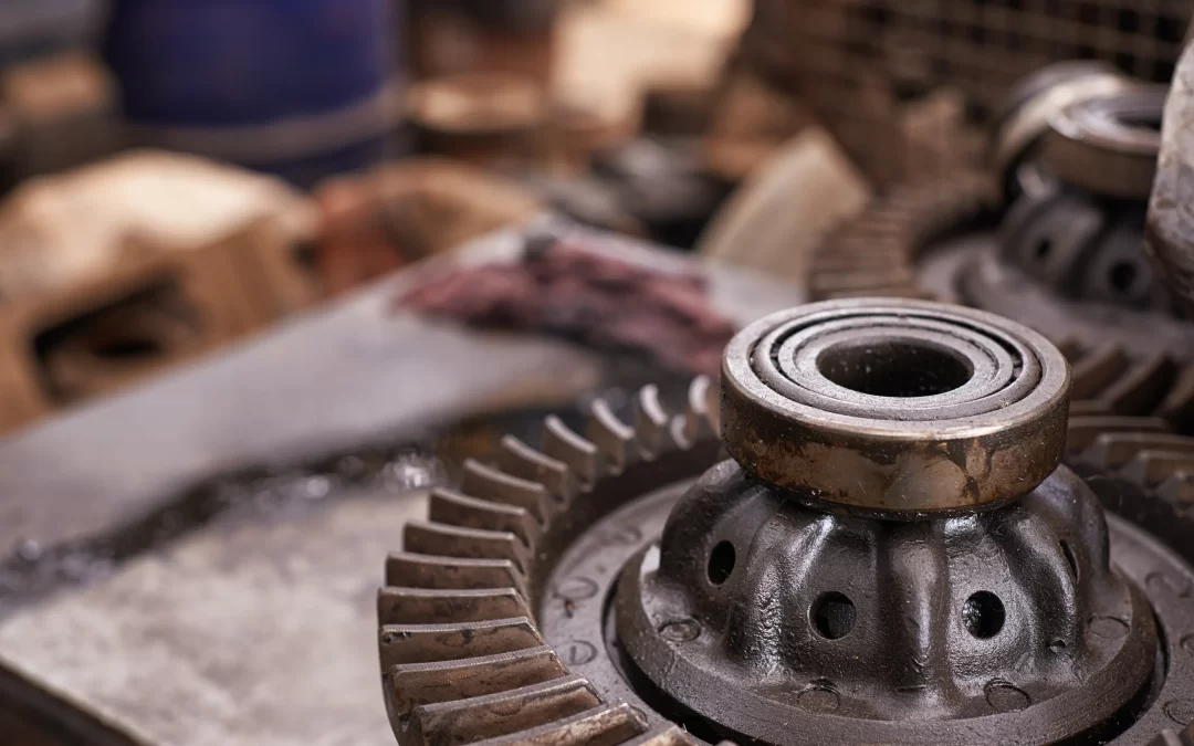 A close-up image of used parts, greasy bearing sitting atop a pile of assorted metal parts and gears in a scrapyard.